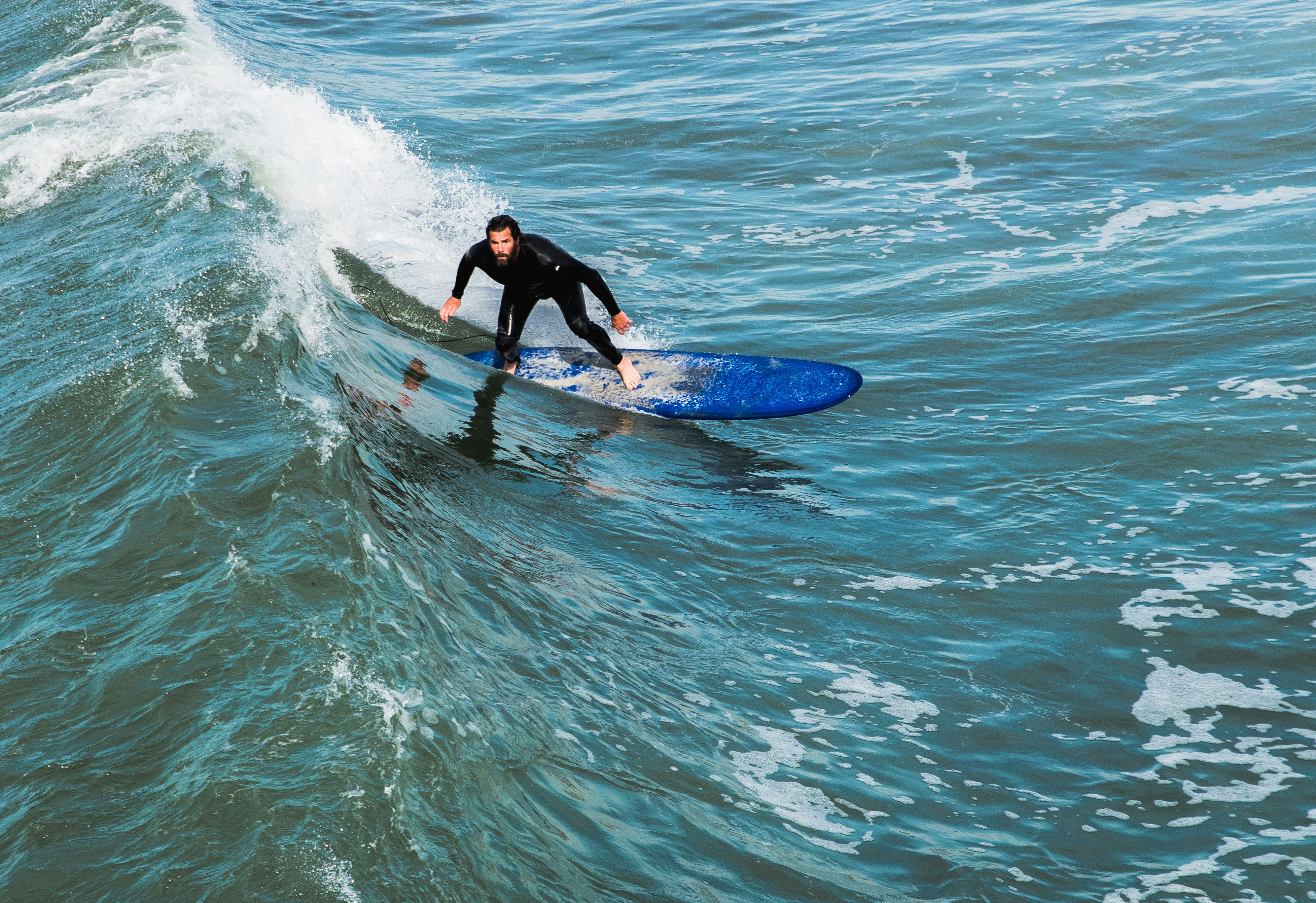 man in black wet suit surfing on wave during daytime